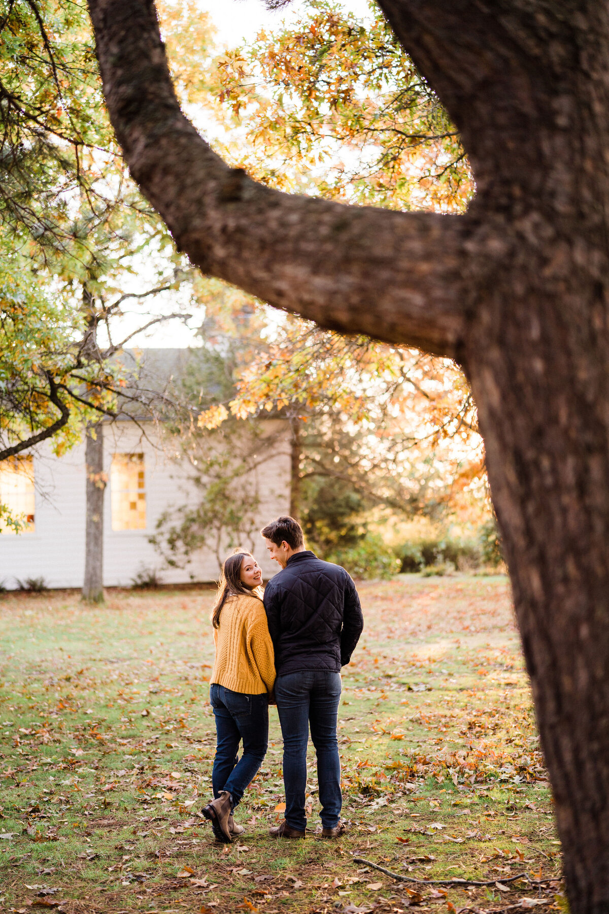 Woman looks with love and affection at partner, under tree with fall colors at best place for engagement photos in Seattle
