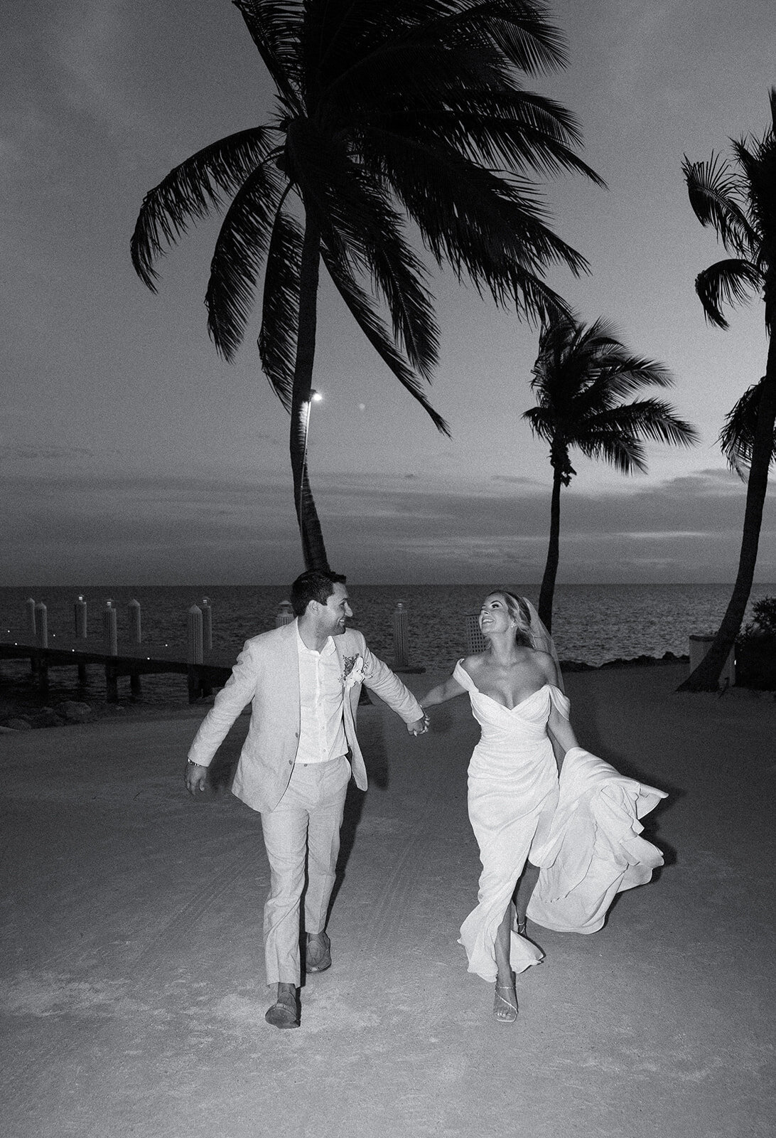 A romantic black-and-white capture of the couple running under the palm trees, illuminated by the moon.