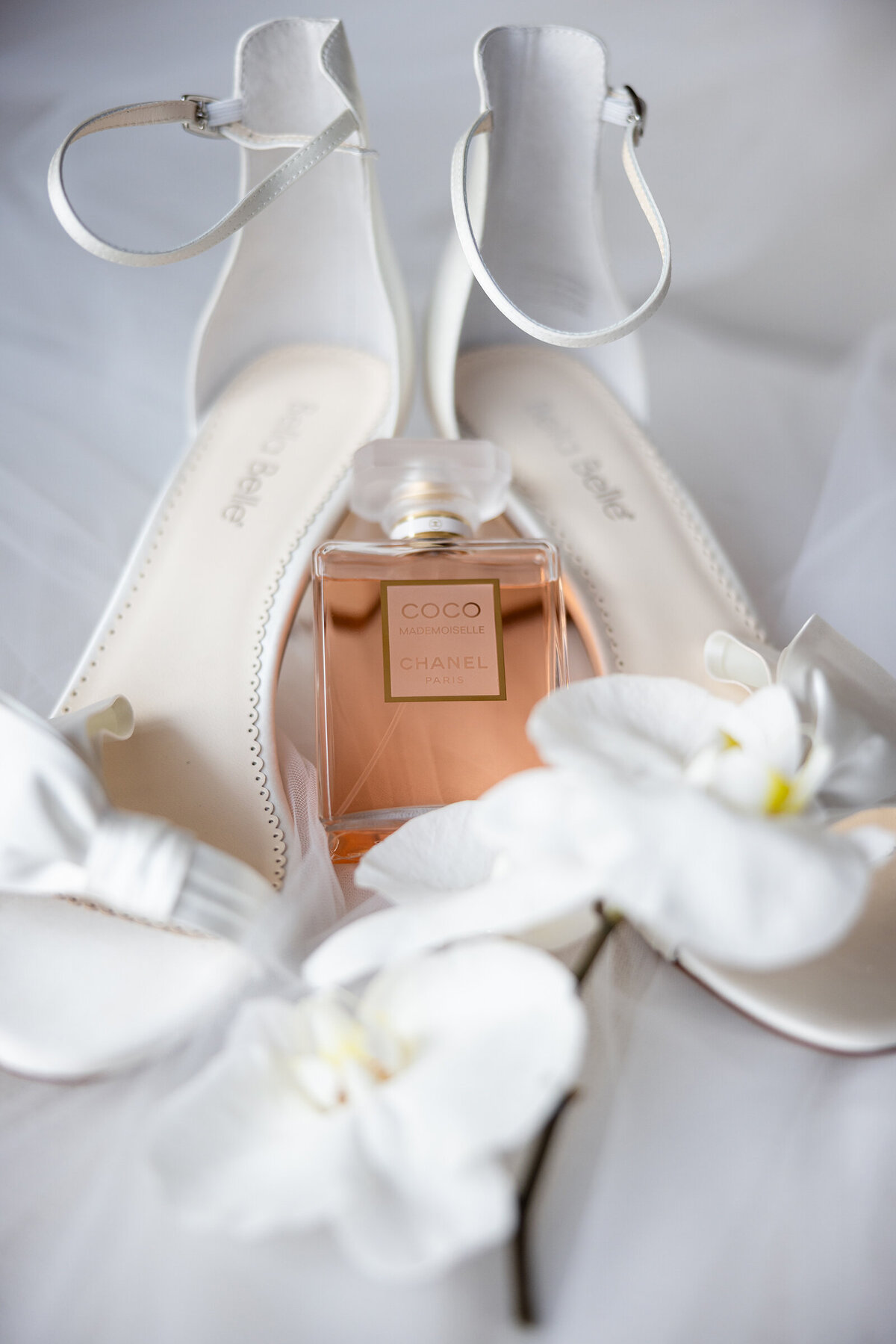 True to color wedding detail picture of white Bella Belle sandals, Coco Chanel perfume bottle and Orchid
