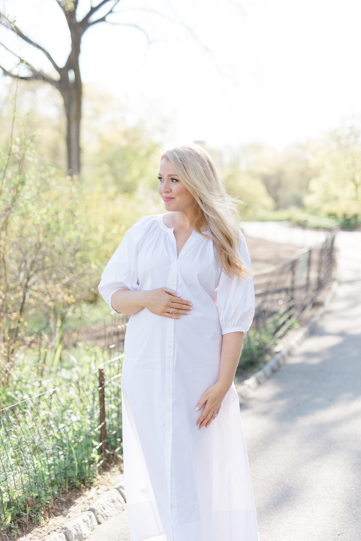 Mom posing in white dress for maternity photos in NYC