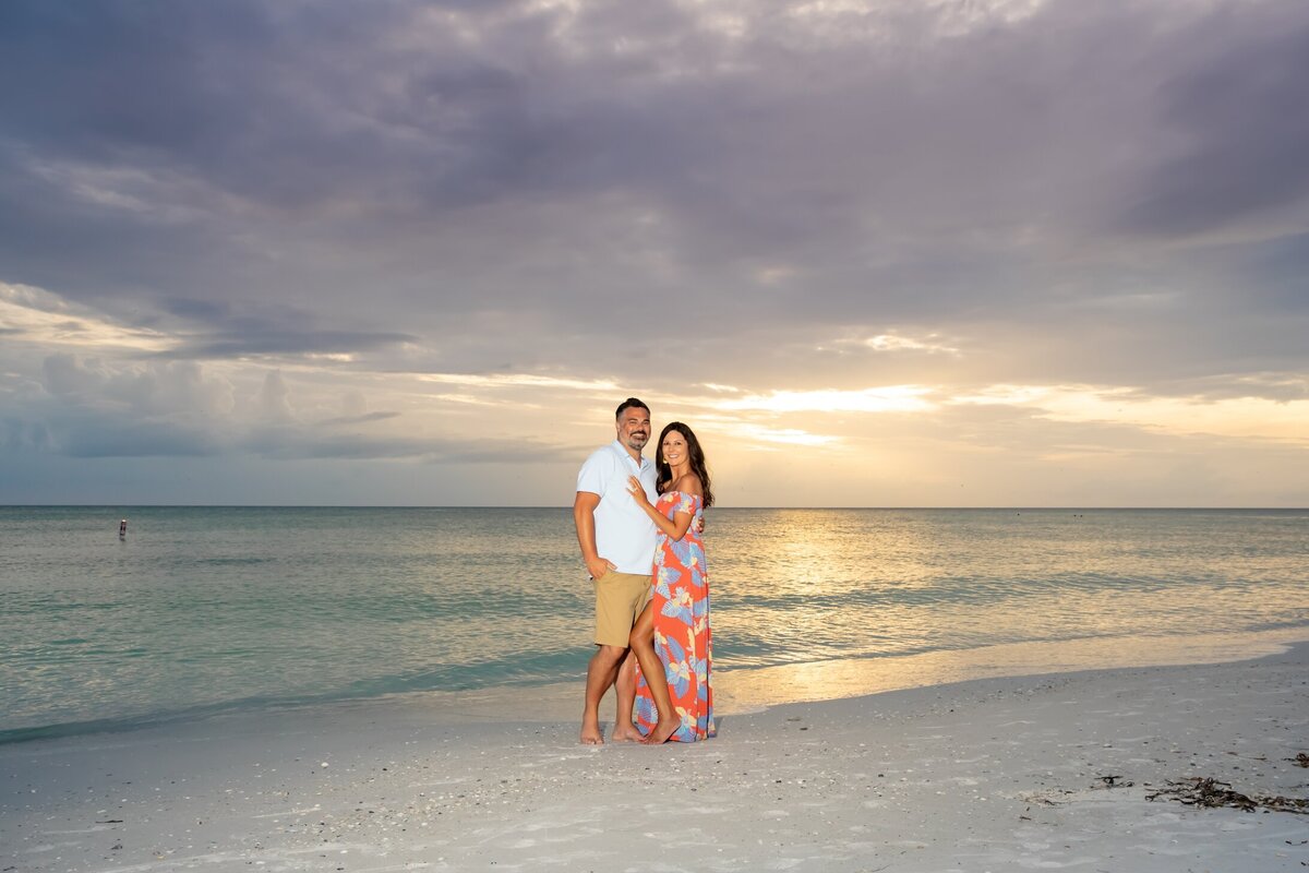 A wide angle of engaged couple with a beautiful Anna Maria Island sunset behind them