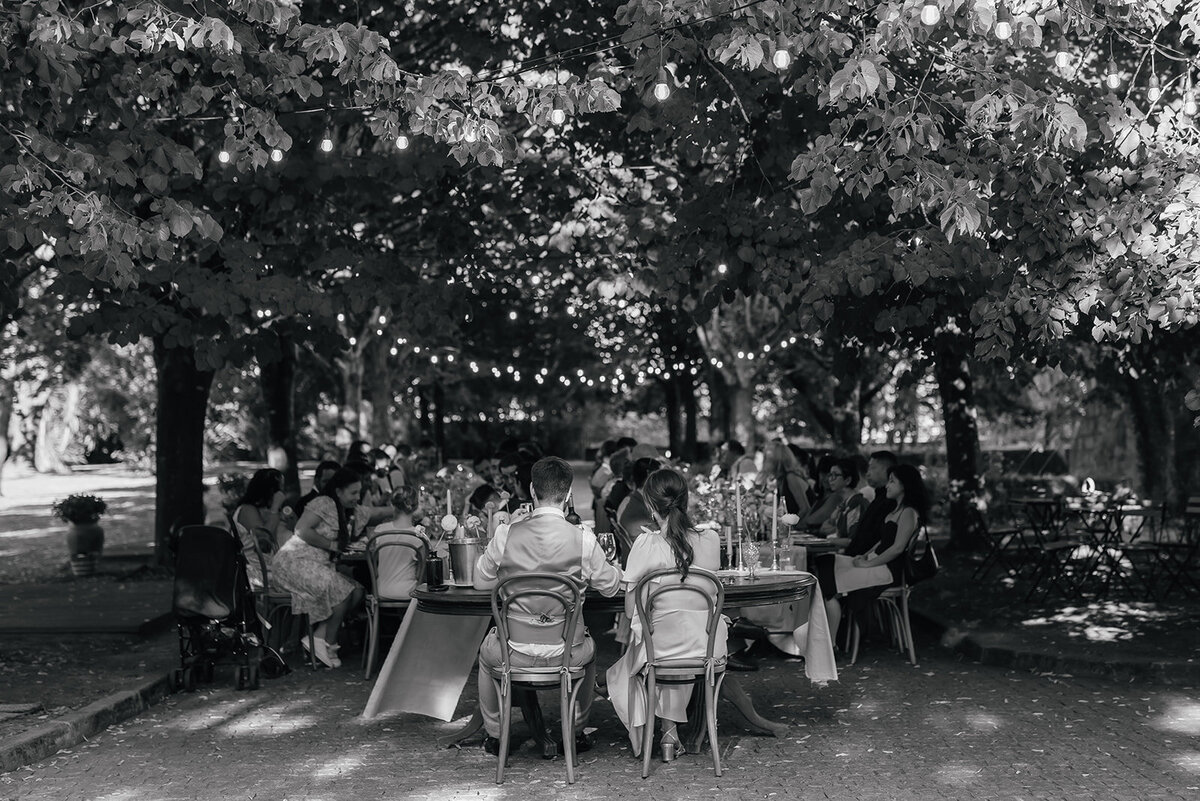 Couple sitting at their wedding table under the trees with fairy lights at Casa Grande de Fontao in Portugal
