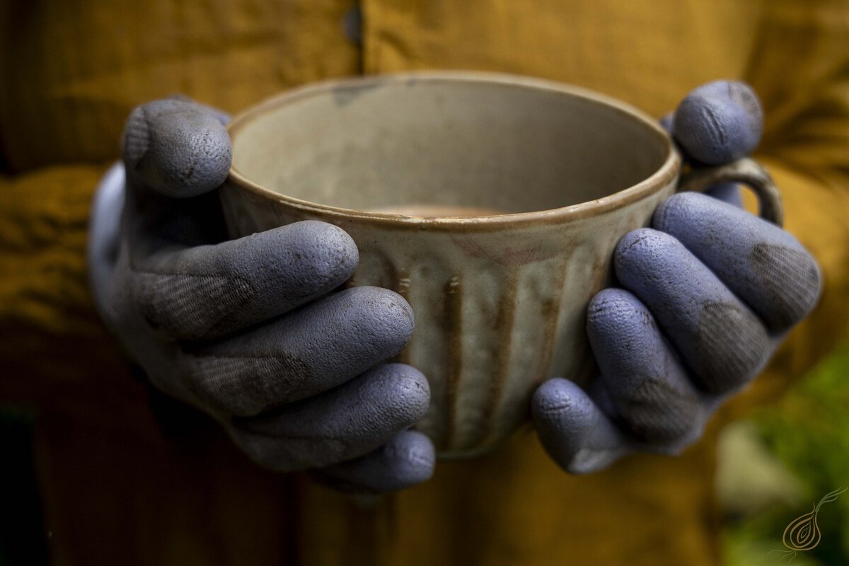 A person holding a steaming cup of coffee, enjoying a moment of relaxation and warmth.