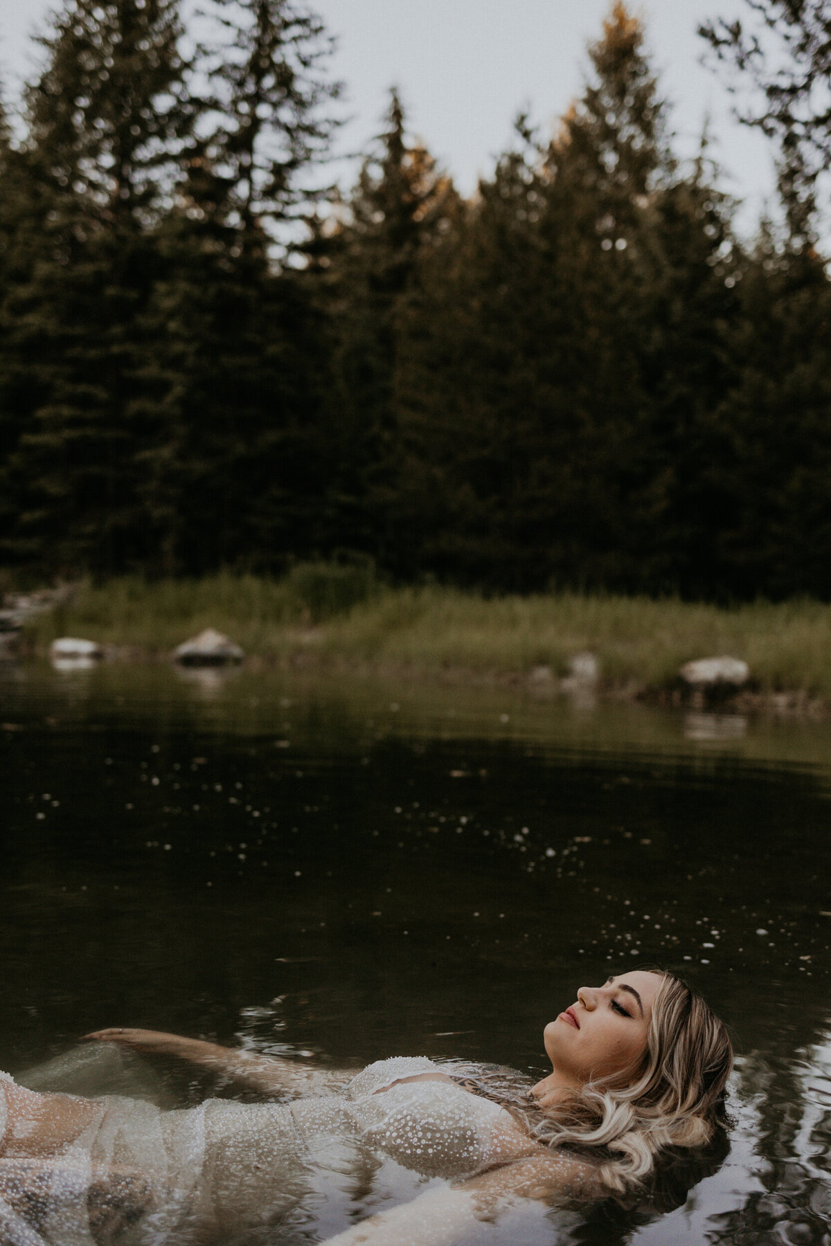 bride floating in a pond in her wedding dress