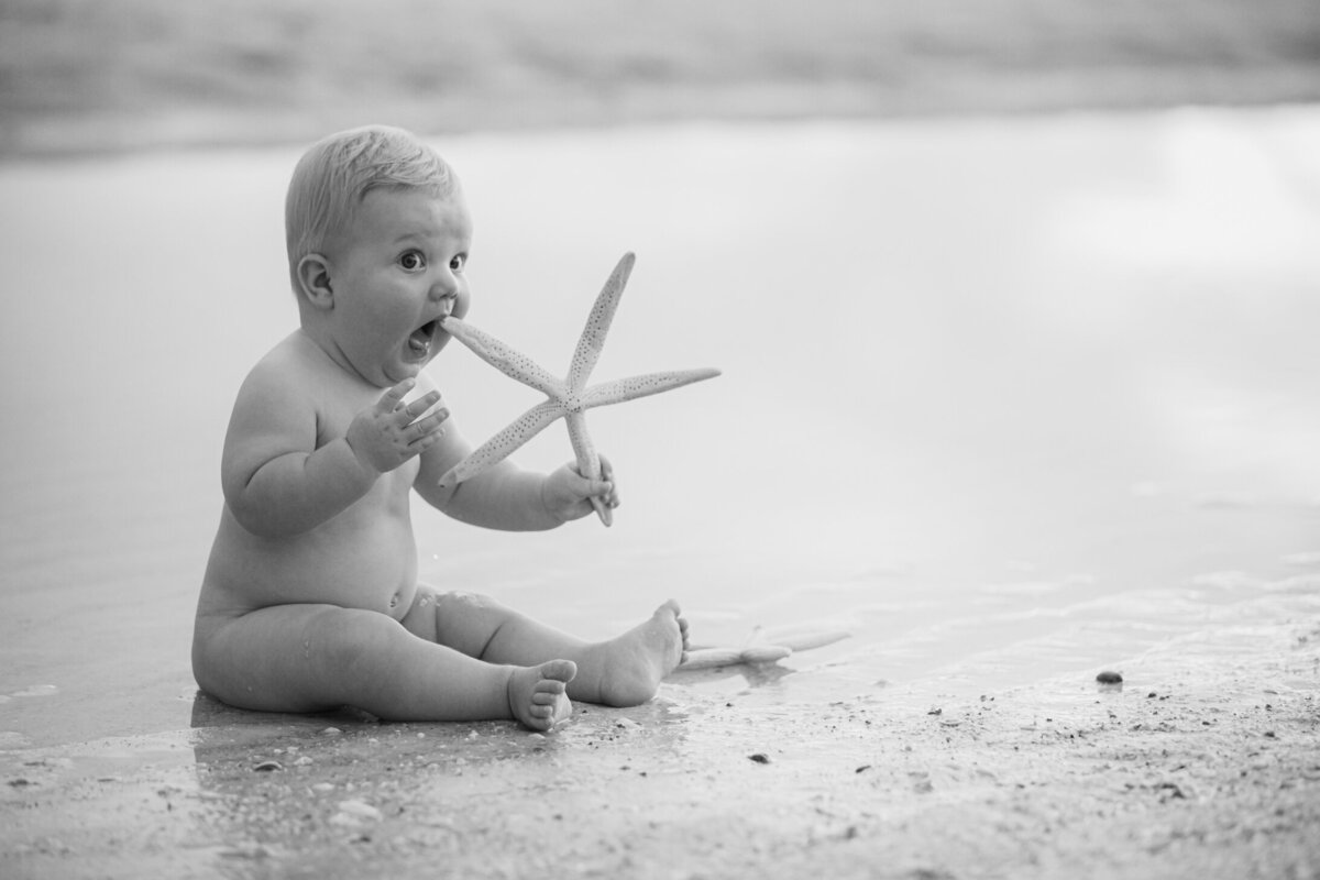 Baby on the beach holding a starfish