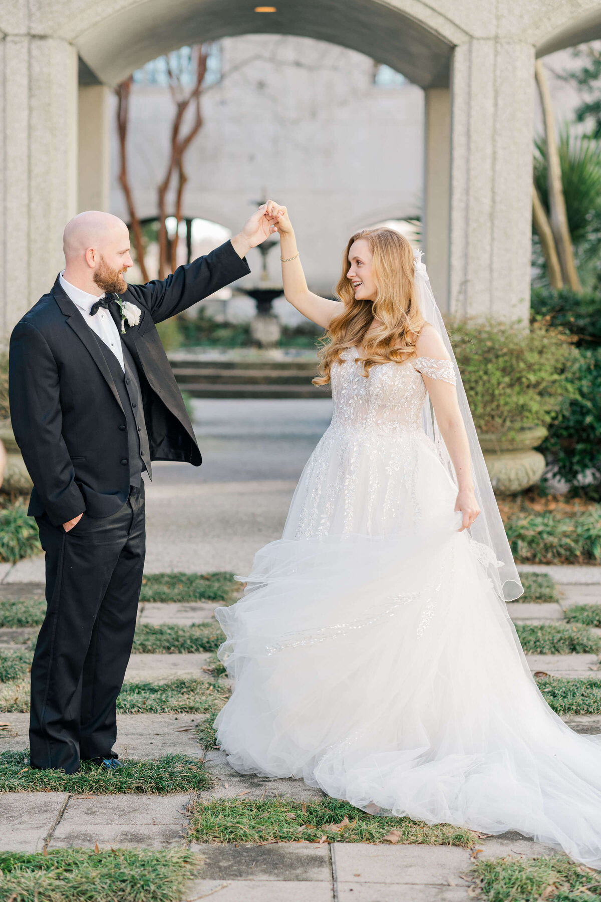 Groom holding brides hand spinning her while she dances