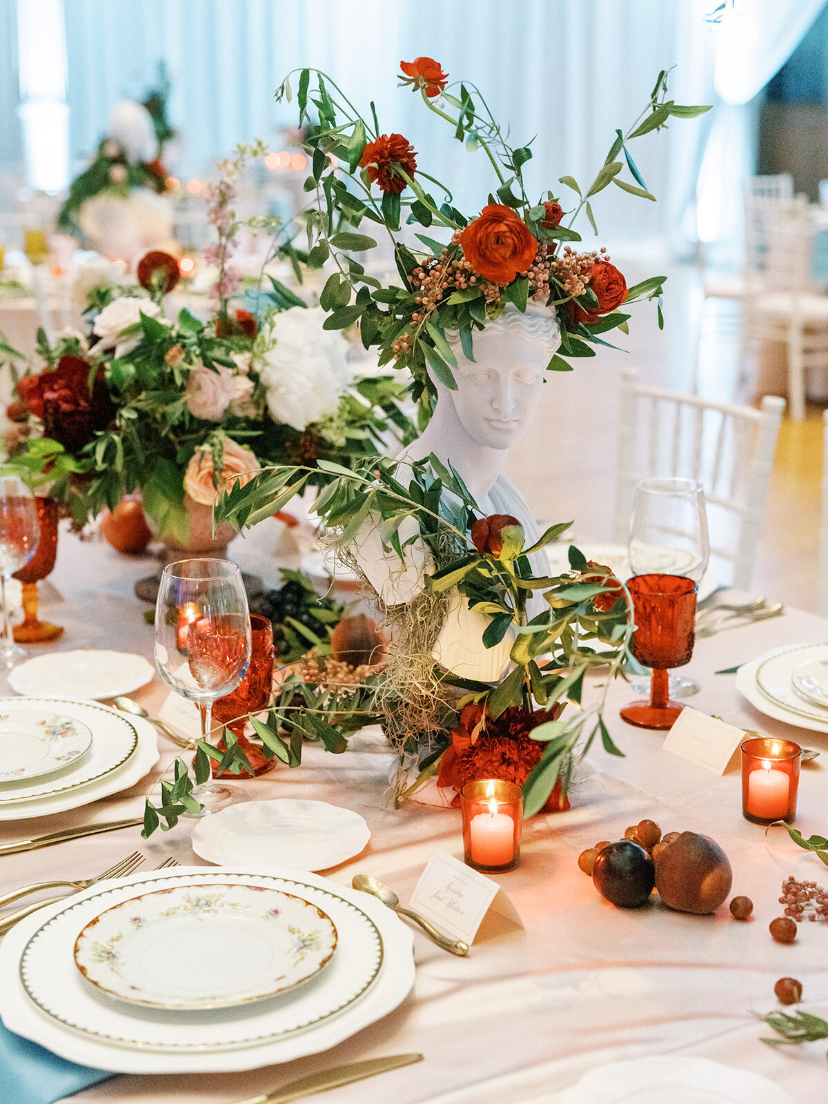 Beautiful reception adorned with marble busts covered in florals and lush centerpieces. The summer solstice color palette was filled with garden roses, peonies, ranunculus, pepper berry and fresh fruit. Design by Rosemary and Finch in Nashville, TN.