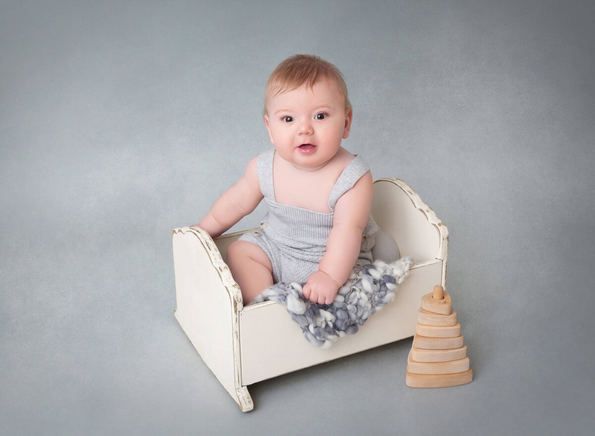 6-month-old baby boy smiling during his photoshoot in New York City. Professional NYC baby photographer specializing in baby milestone photography