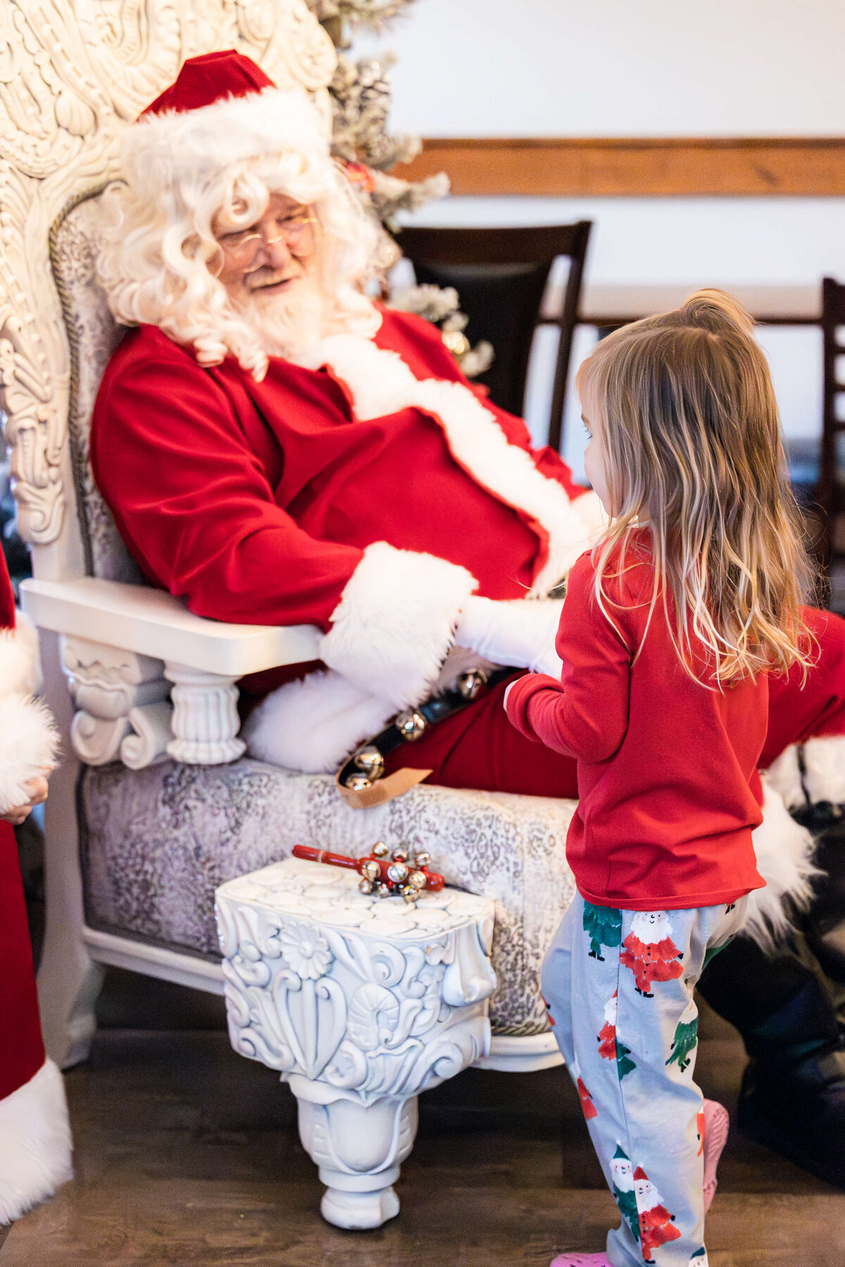 Santa clause sitting in a chair talking to a child in fayetteville NC captured by Liza Hondros Photography