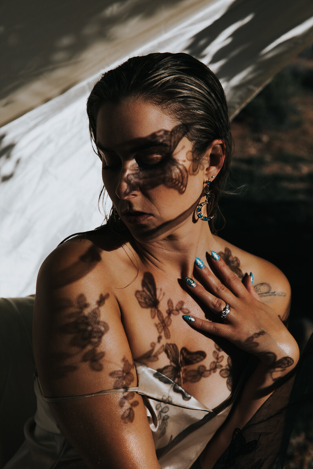 woman posing with her hand on her chest and butterfly shadows on her face.