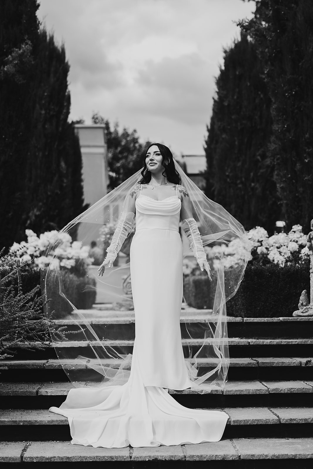 Bride wearing flowing veil and fitted satin wedding dress