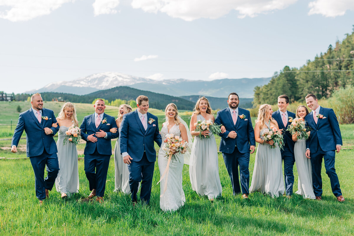 Bridal party together in field by colorado springs wedding photographer