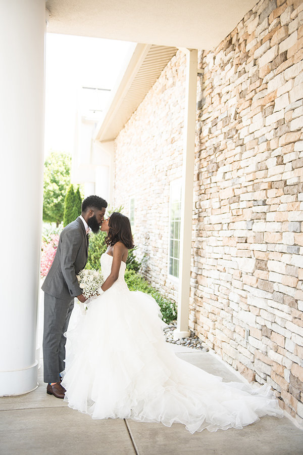 A bride and groom kiss a the church portico