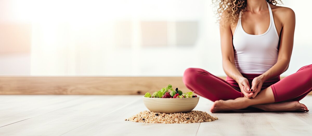 Fit woman sitting crosslegged next to a bowl of salad