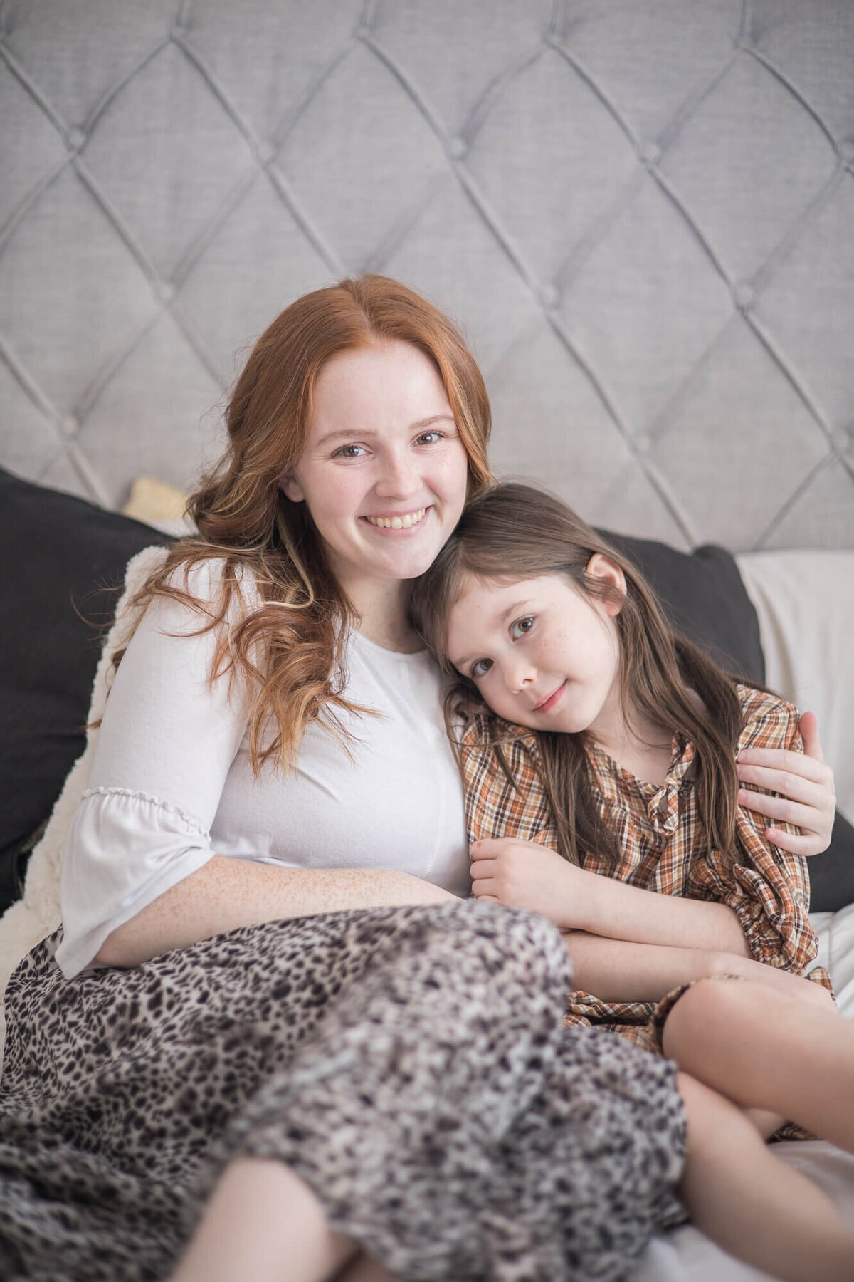 mother and her young daughter sitting together on a bed