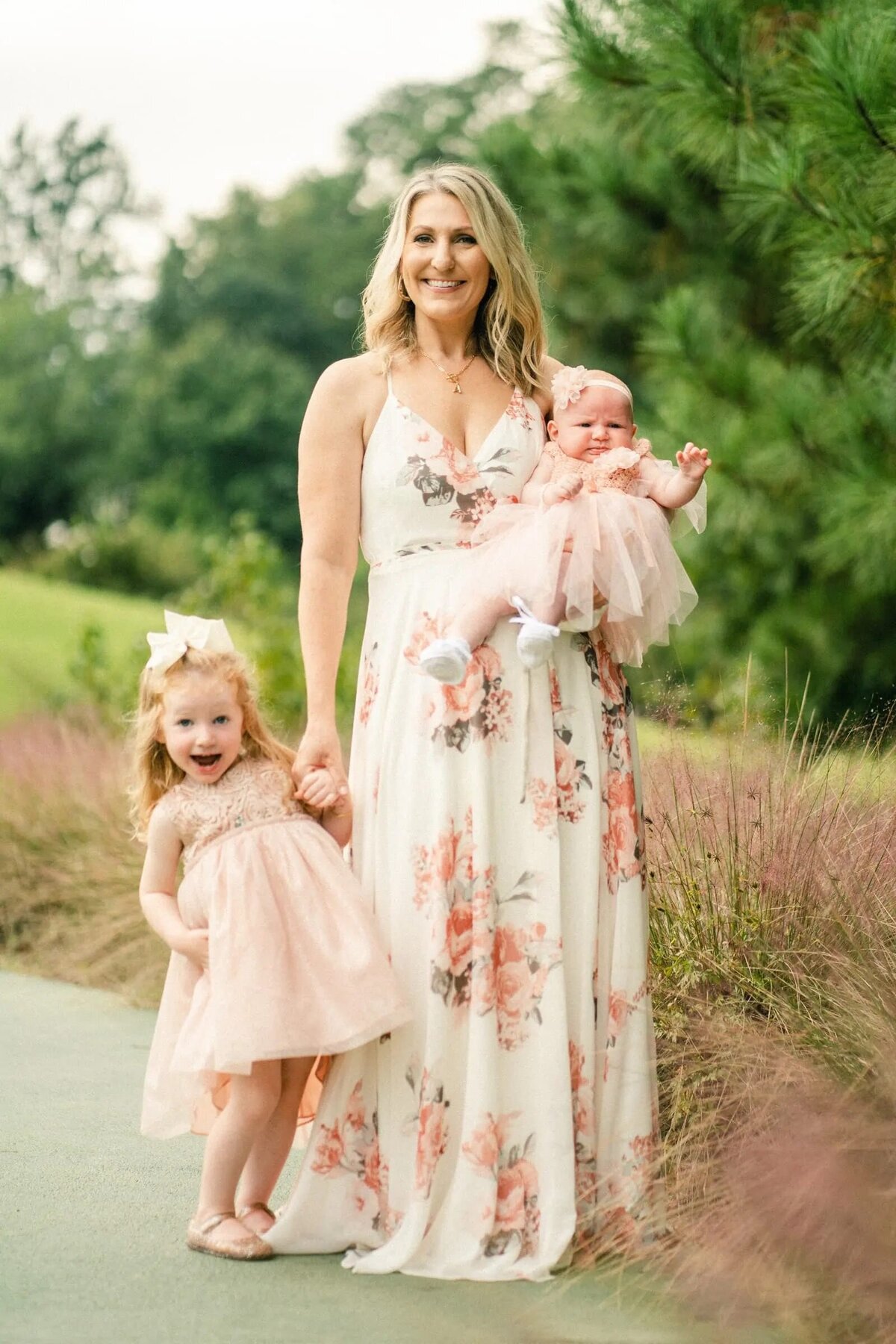 A mom holding a newborn in one arm and a small child standing next to her.