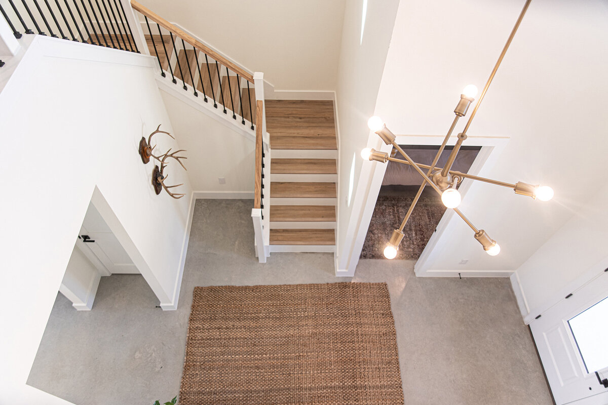 aerial view of living room with white walls and wooden stairs and vertical black metal guardrail