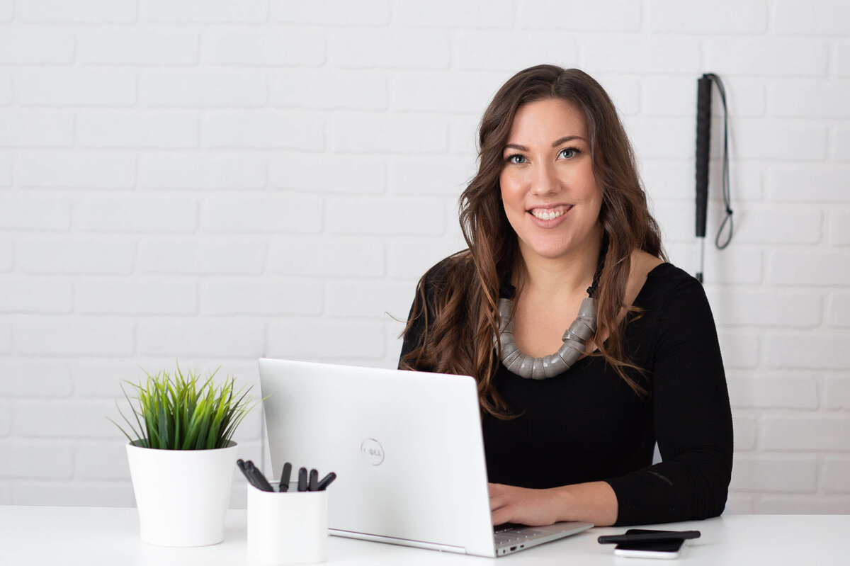 Ottawa branding photography of a woman in a black top sitting at a desk working at her computer.  Captured in studio by JEMMAN Photography COMMERCIAL