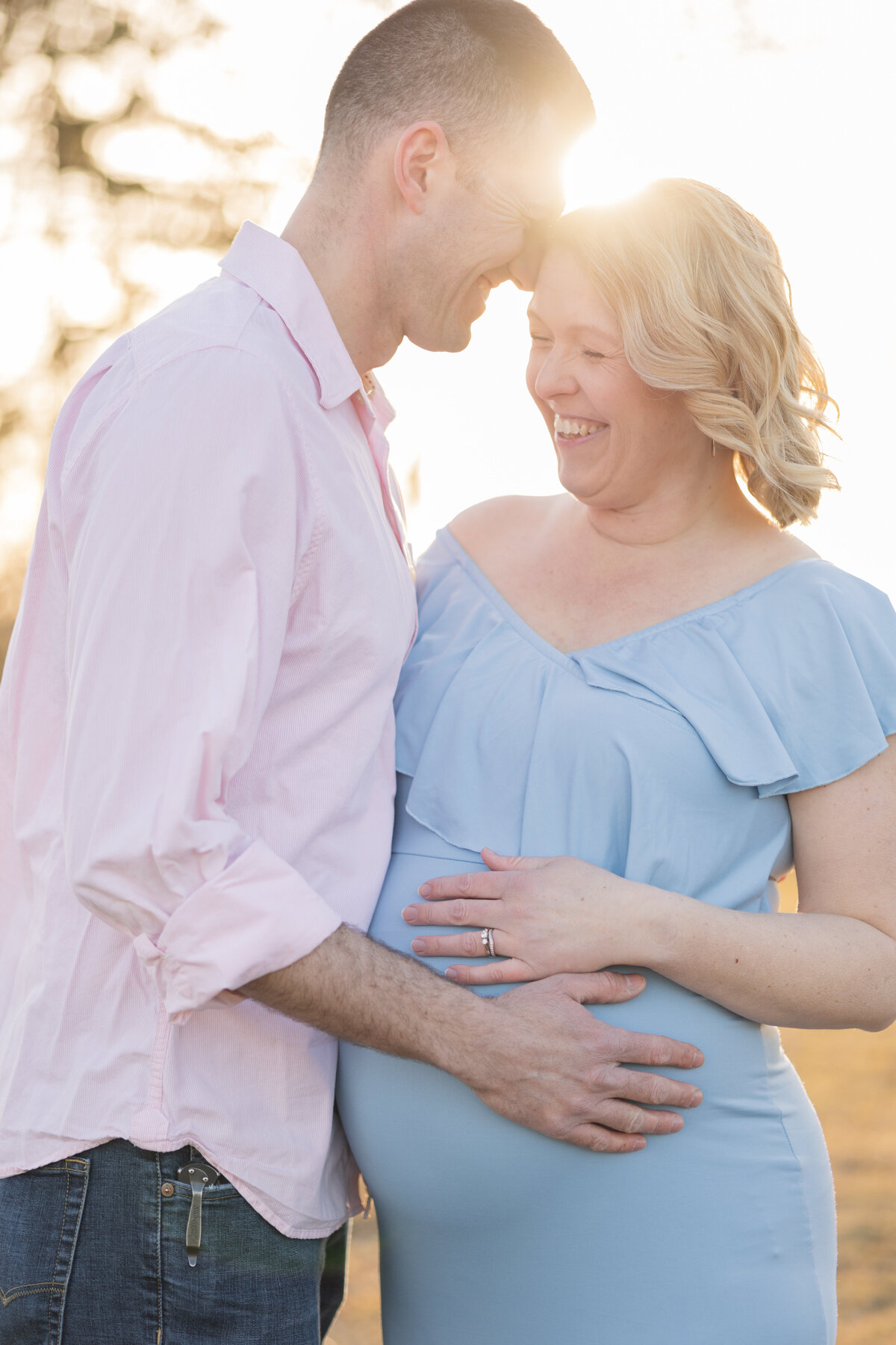 Pregnant couple standing  with hands on pregnant belly