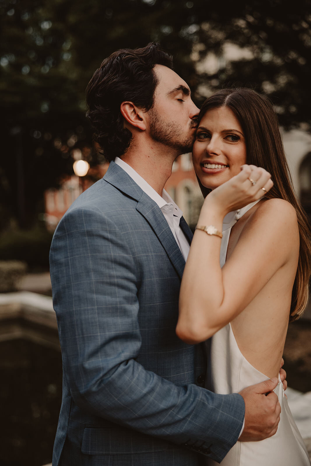 A person kissing their partner's head as they smile 