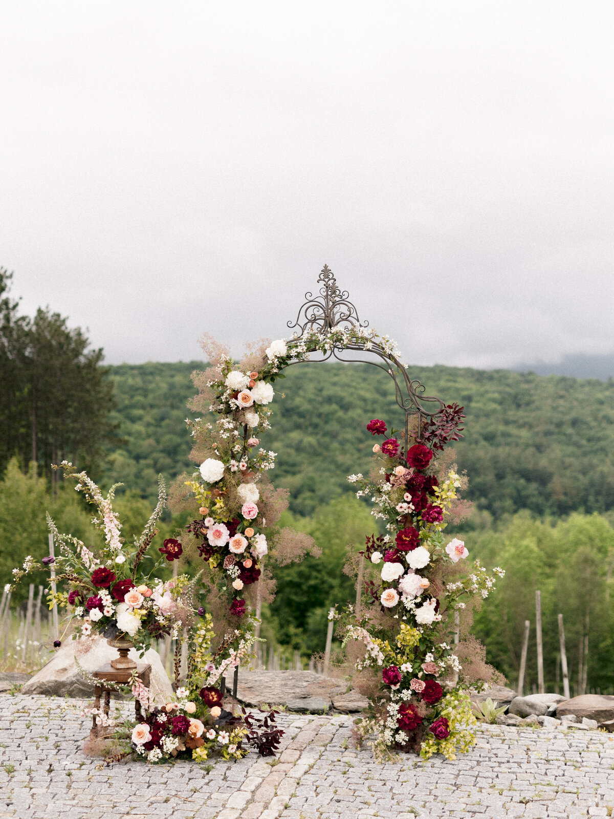 An airy arch of red and pink flowers in front of green hills at Chateau St Agnes.