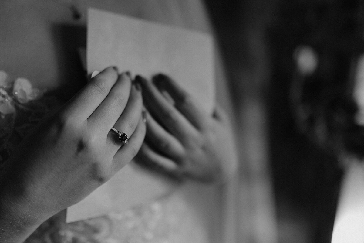 Close-up cinematic shot of a groom adjusting his bow tie, photographed in fine art black-and-white by Scottish wedding photographer Aly Robinson.
