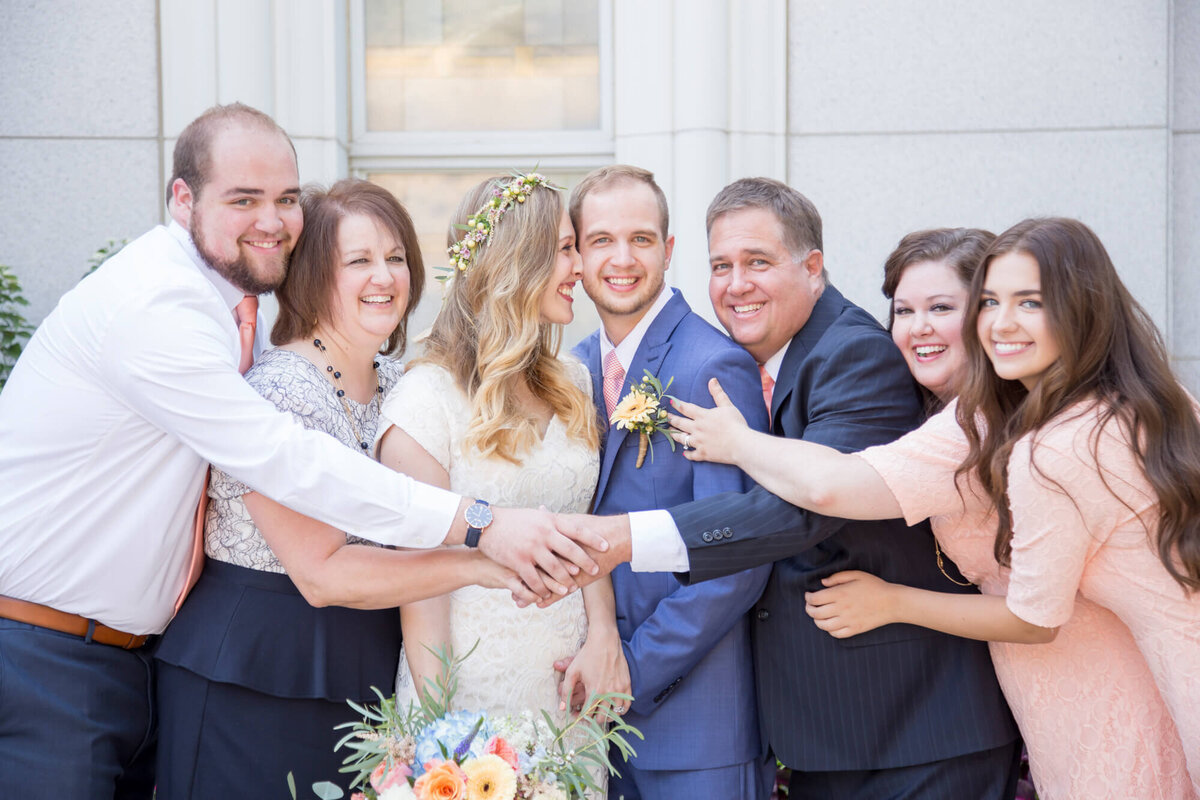 wedding couple with family hugging on wedding day