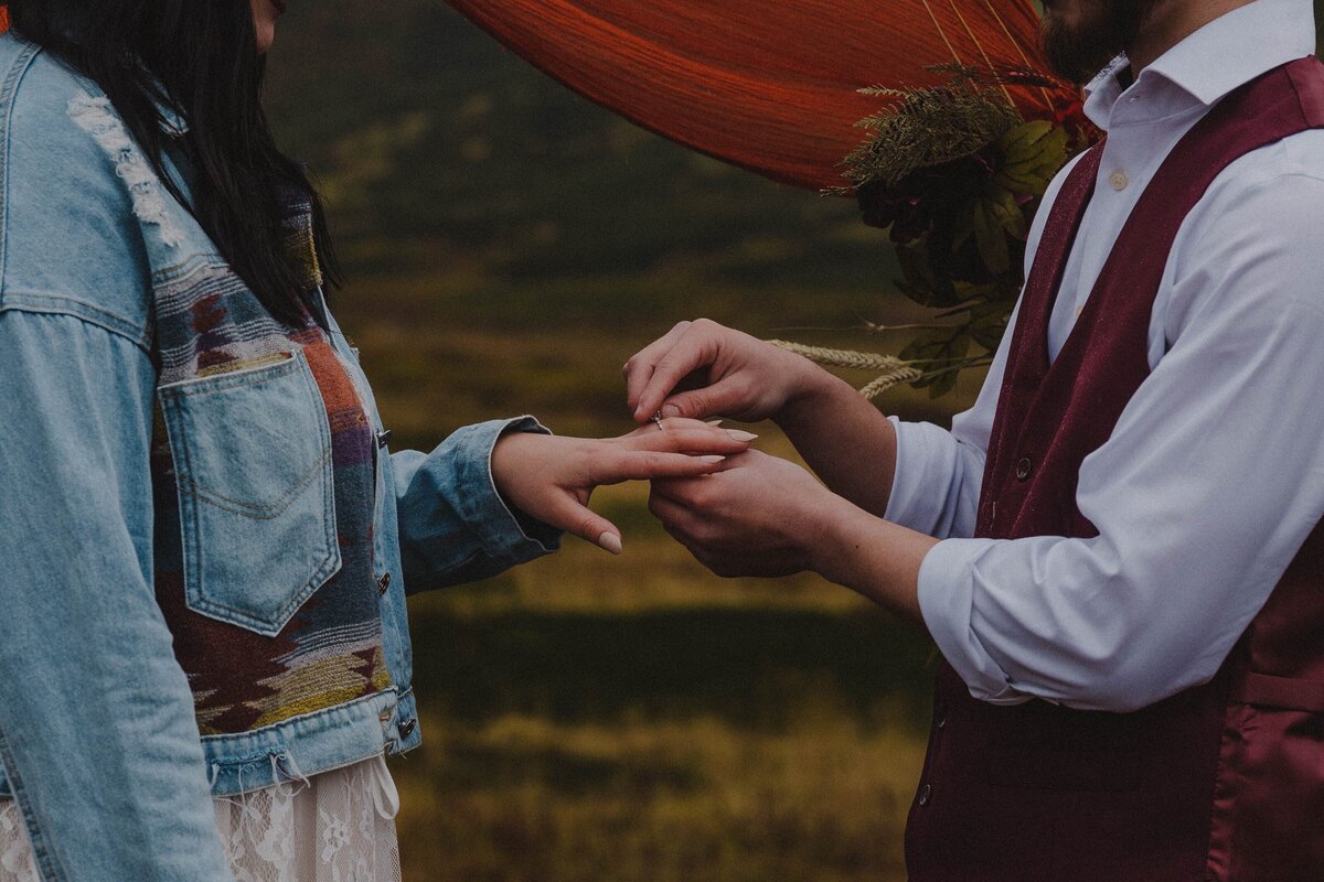 A couple says their vows and swap rings during their elopement in Alaska