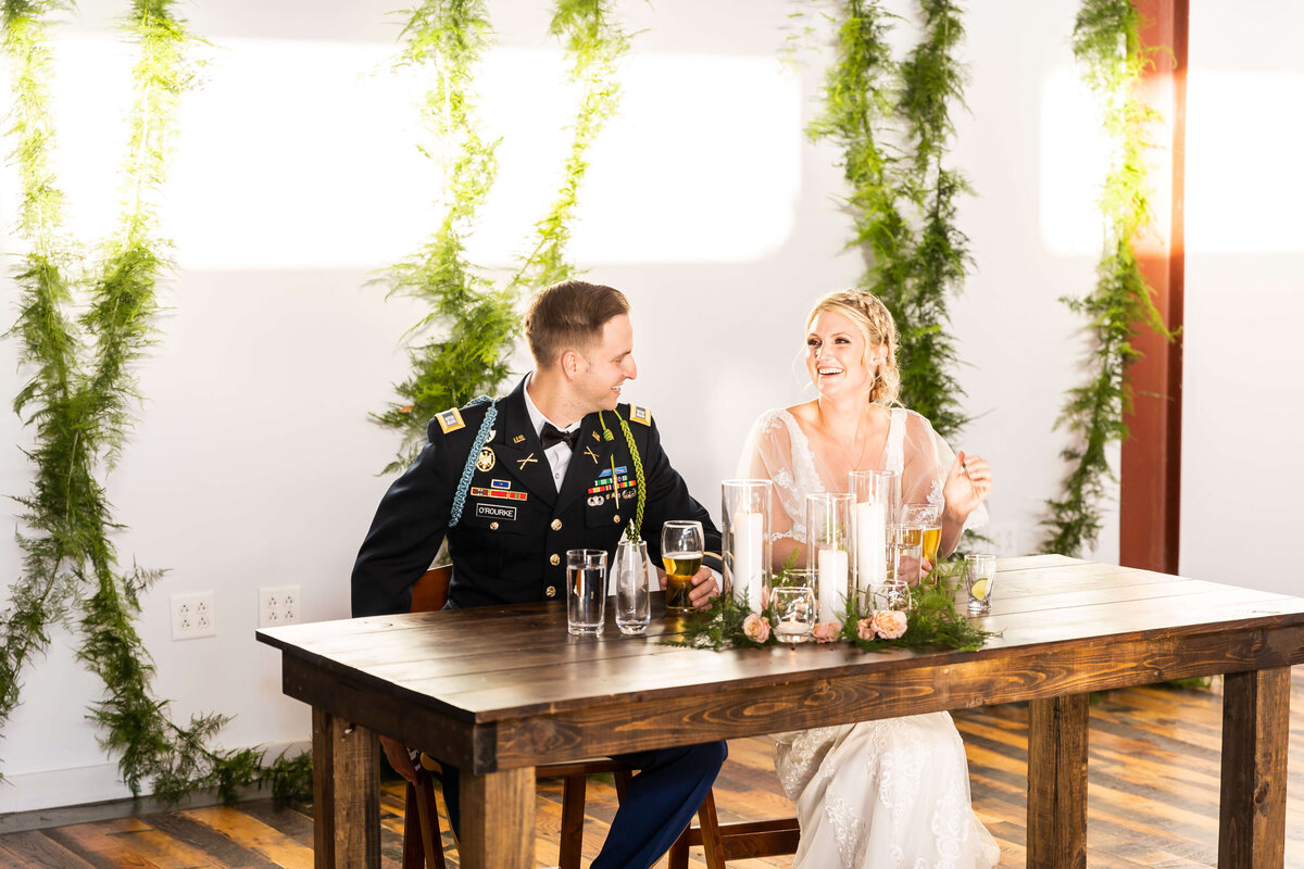 bride and groom sat at sweetheart table at Fat Bottom Brewery wedding reception in Nashville, TN