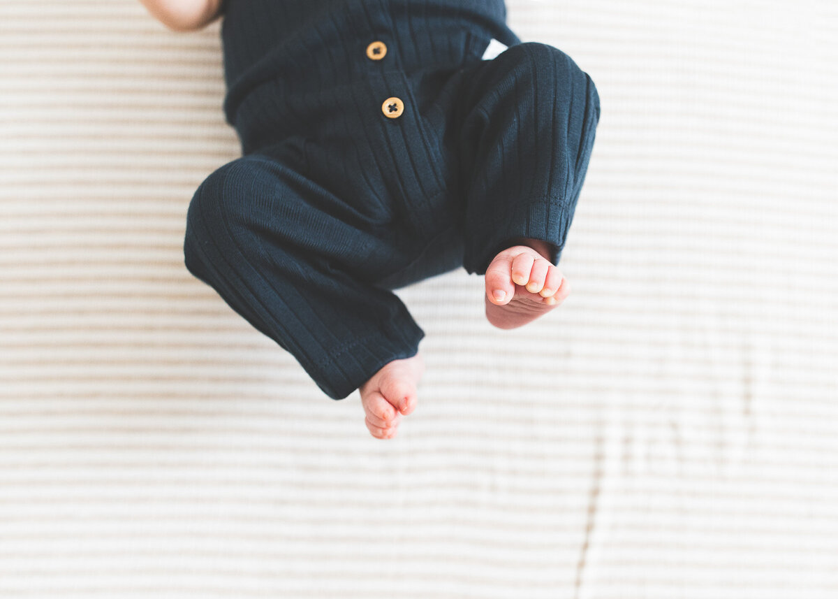 Photo of newborn baby feet on neutral striped blanket by newborn photography Portland, Or.