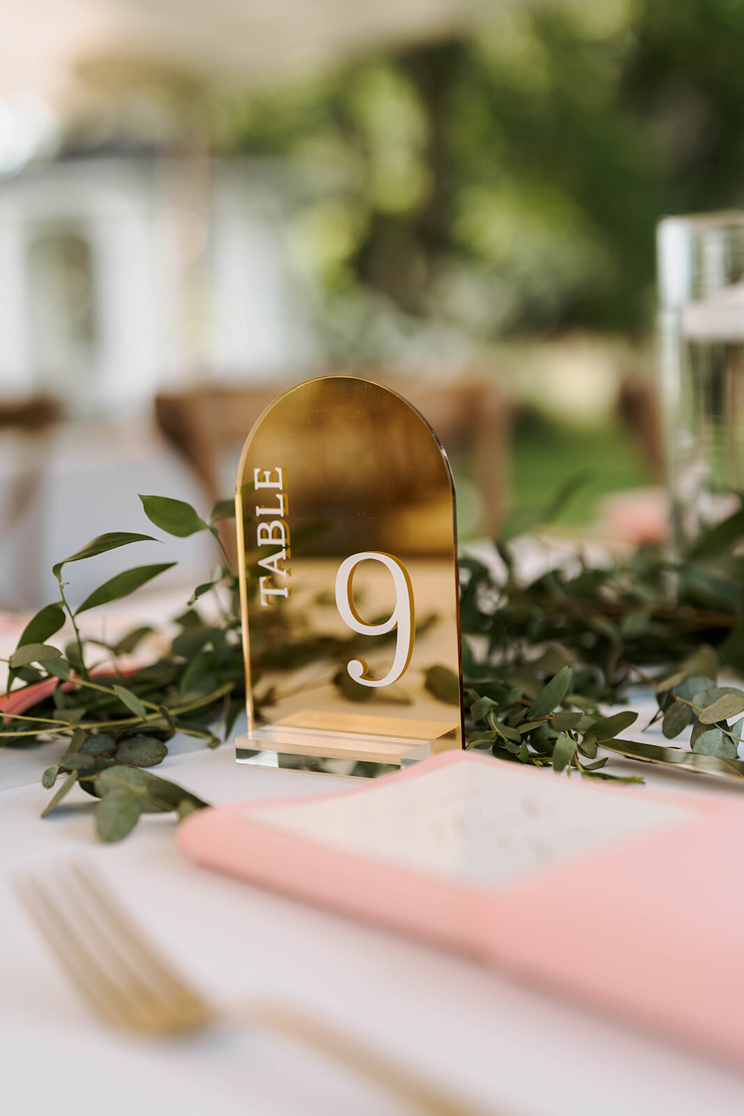 mirror arch gold acrylic table numbers with greenery and blush napkins