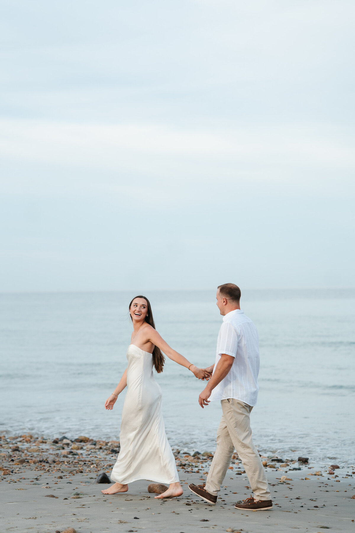 New England beach engagement photos during a sunset coastal session with candid moments.