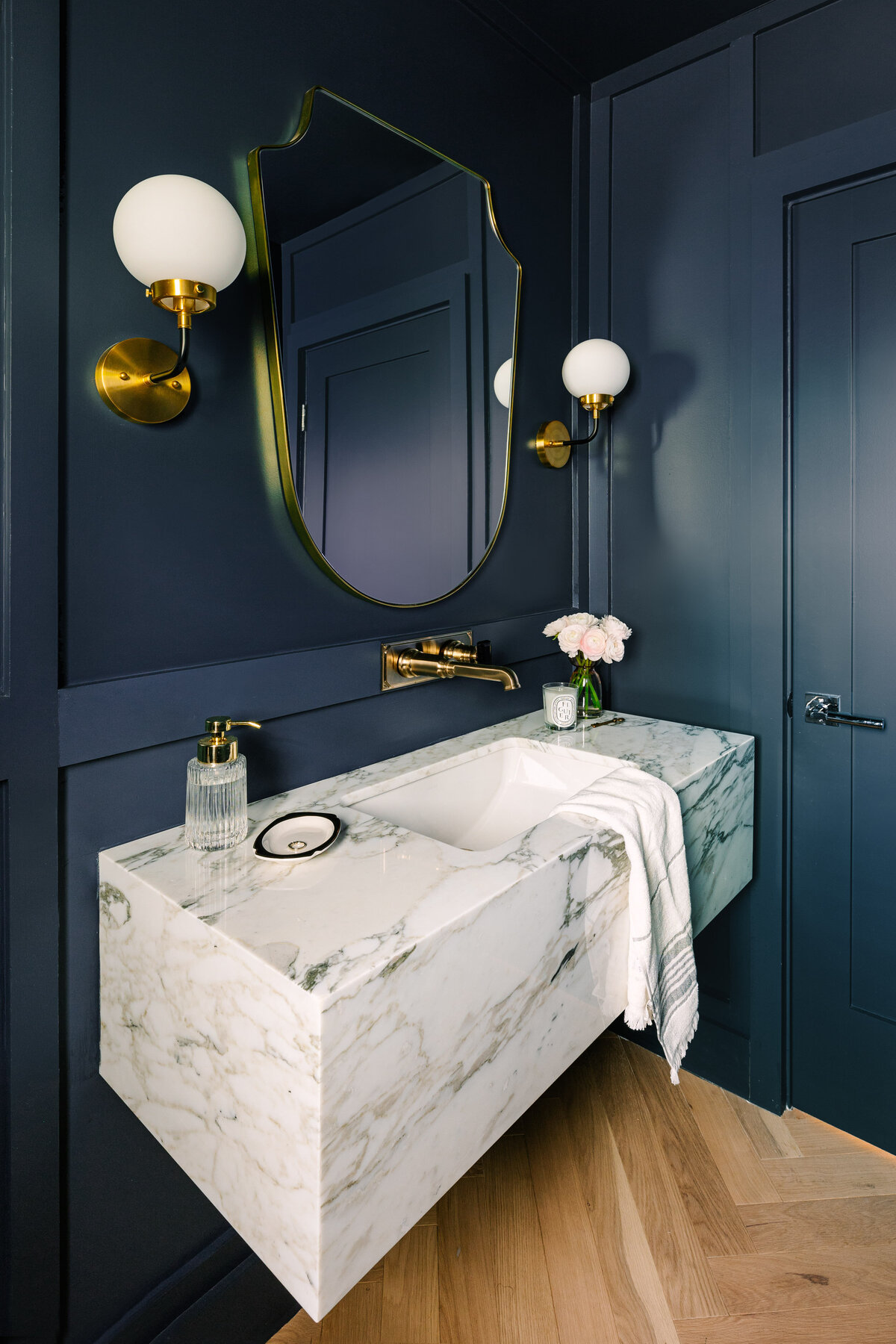 Elegant powder room with Farrow and Ball Hague Blue walls, Corchia marble floating vanity and Italian shield mirror.