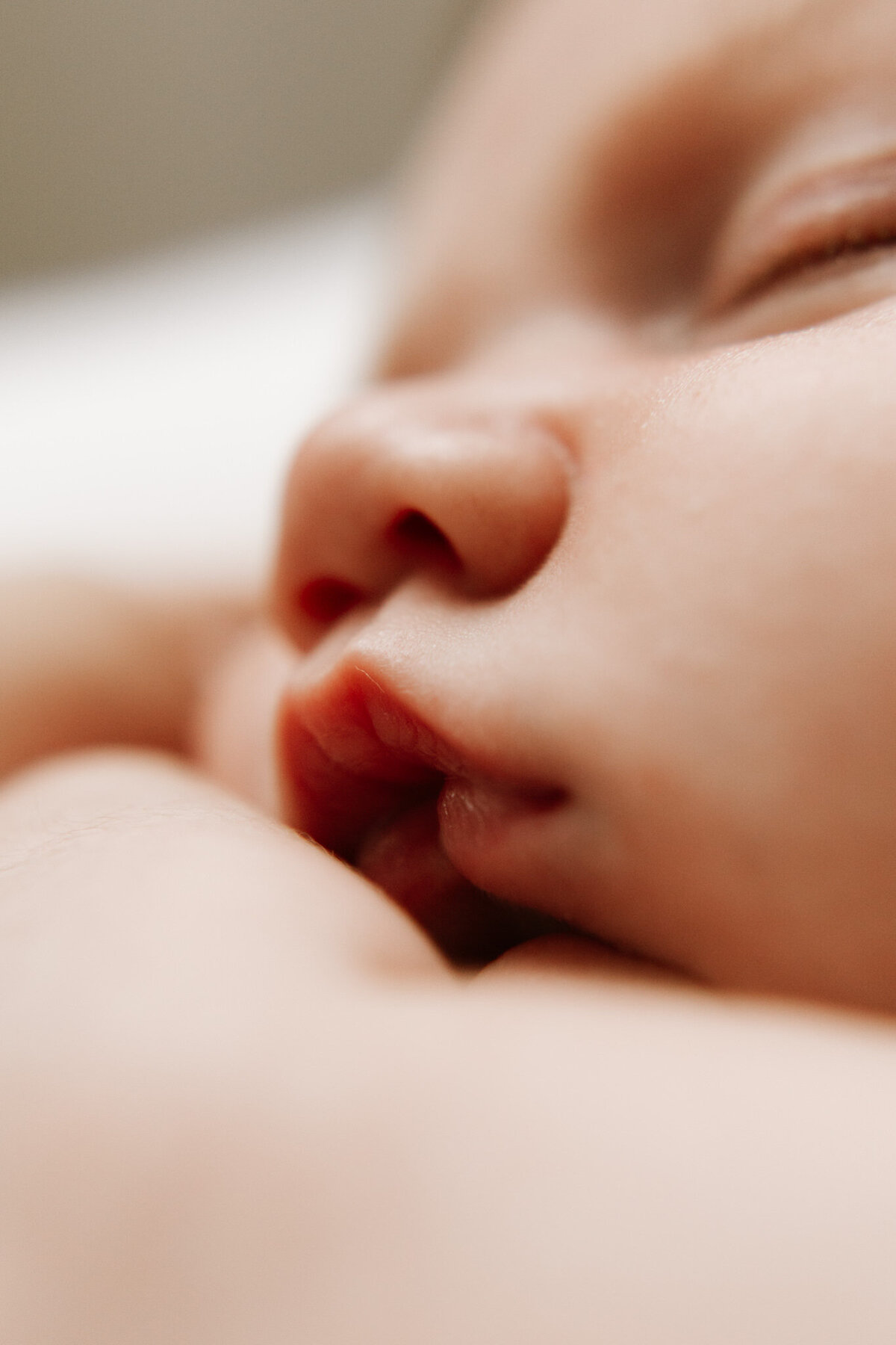 Close-up macro photo of a newborn baby's lips and nose, highlighting delicate features in a soft, warm-toned newborn photography session in Sydney.