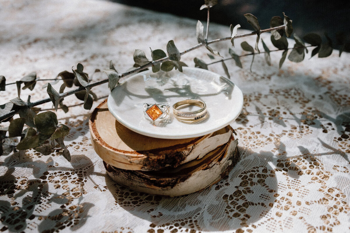 A close-up of a flatlay of  the bride and groom's wedding rings on a plate