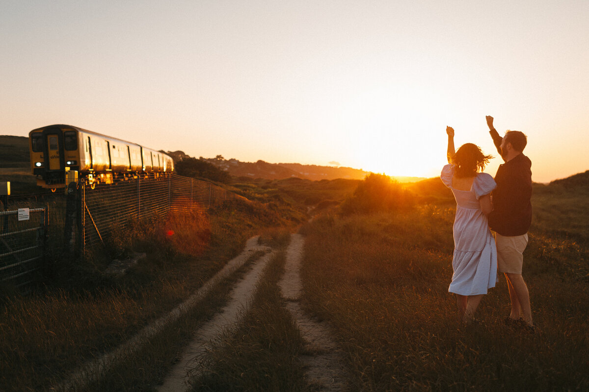 Couple wave to the branch ine train from St Erth to St Ives at Sunset
