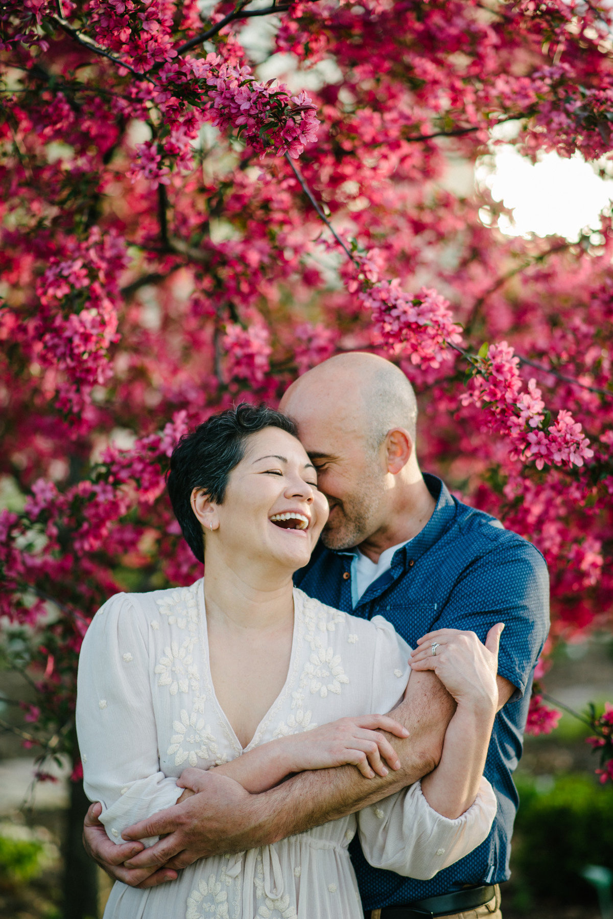 Engagement Photo of couple laughing in front of blooming tree