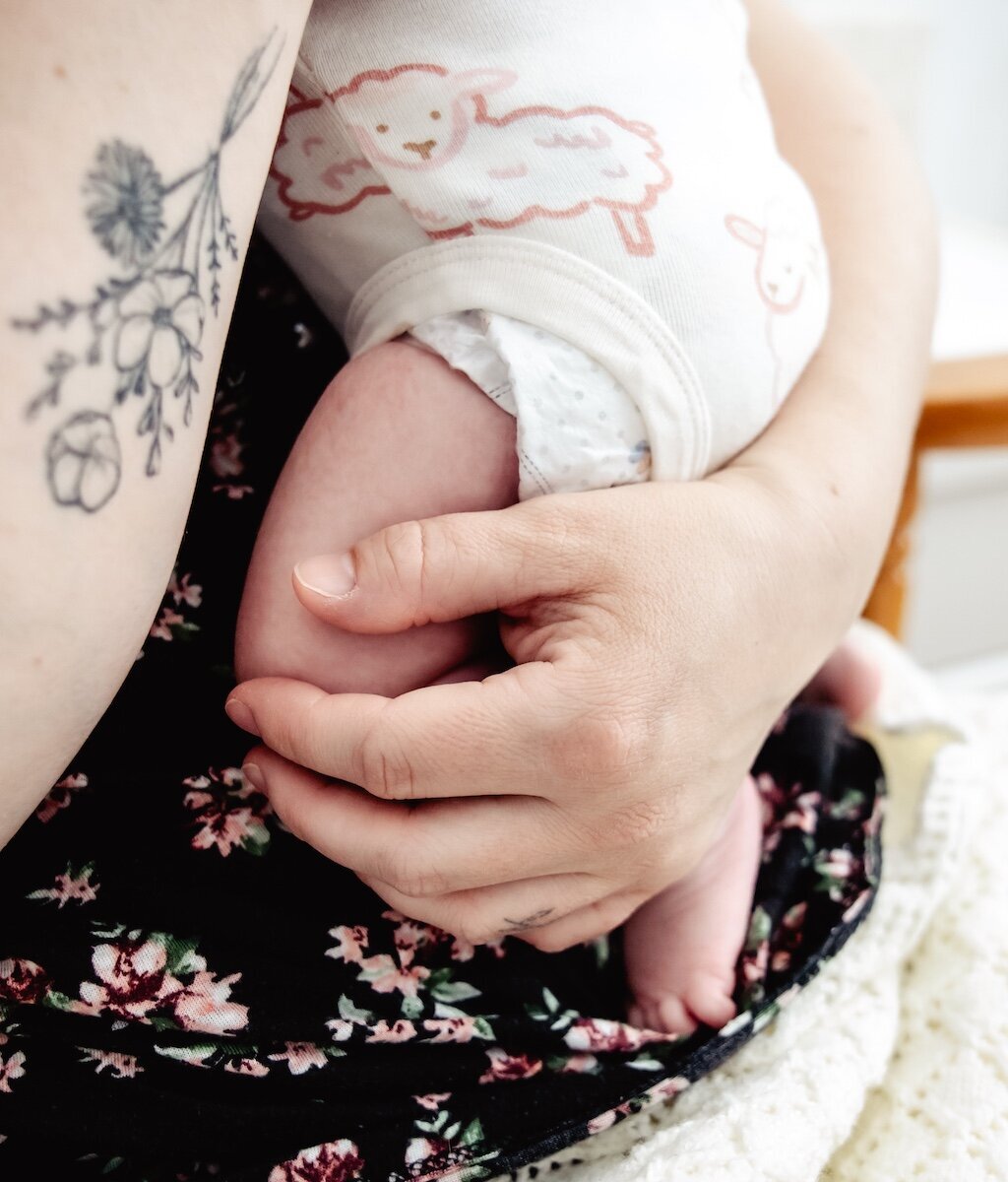 A new mama holds her small newborn baby in her arms