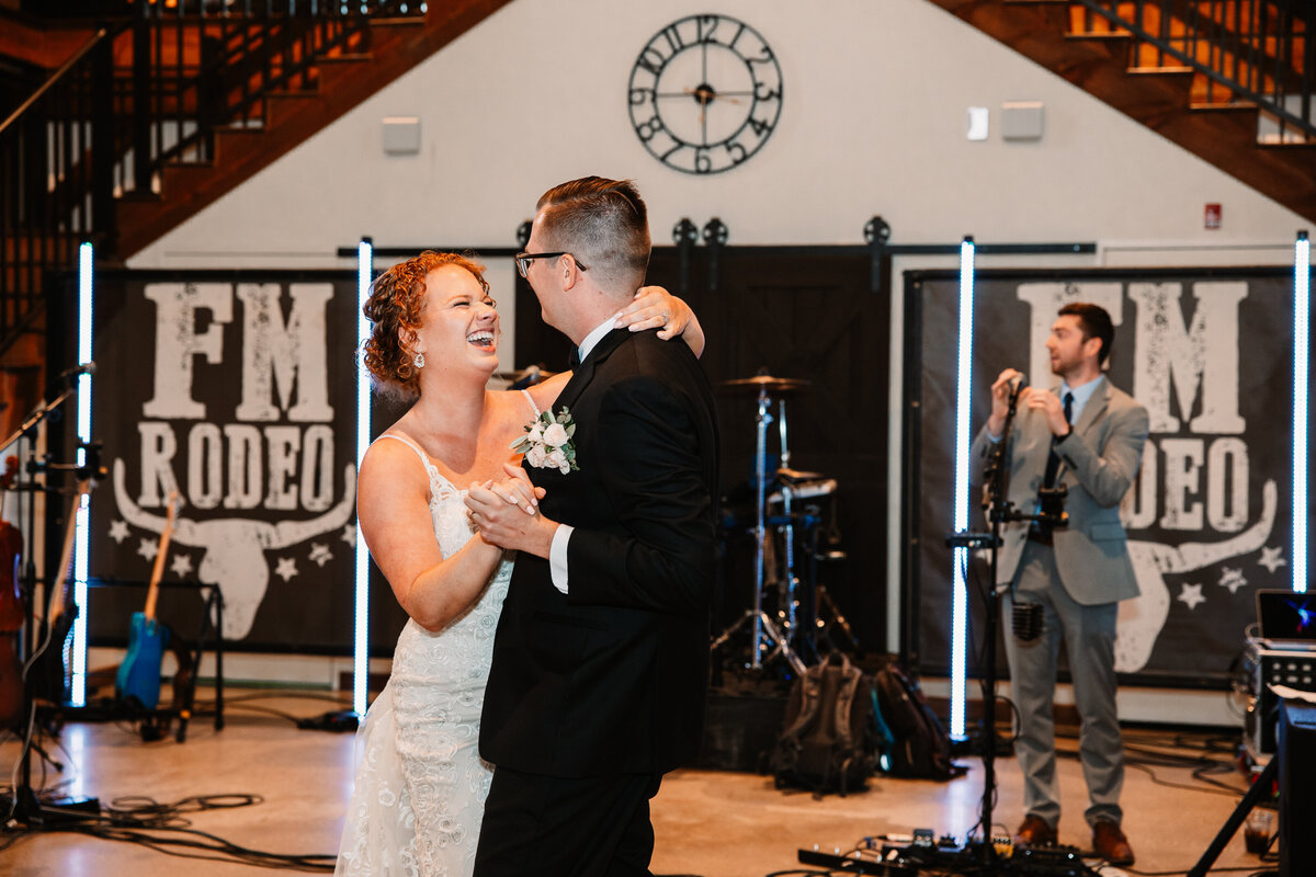 Newlyweds laugh big while dancing for the first time to a live band