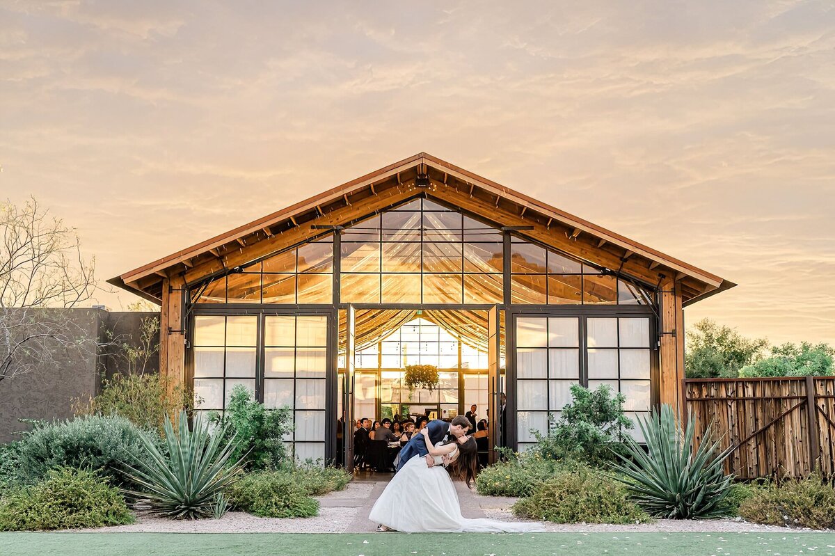 Reception barn at sunset with groom dipping Bride in front