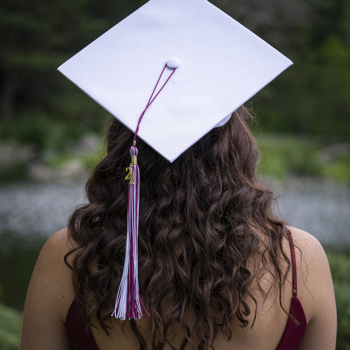 Photo of a high school senior with her back to the camera, showing off her cap and tassel