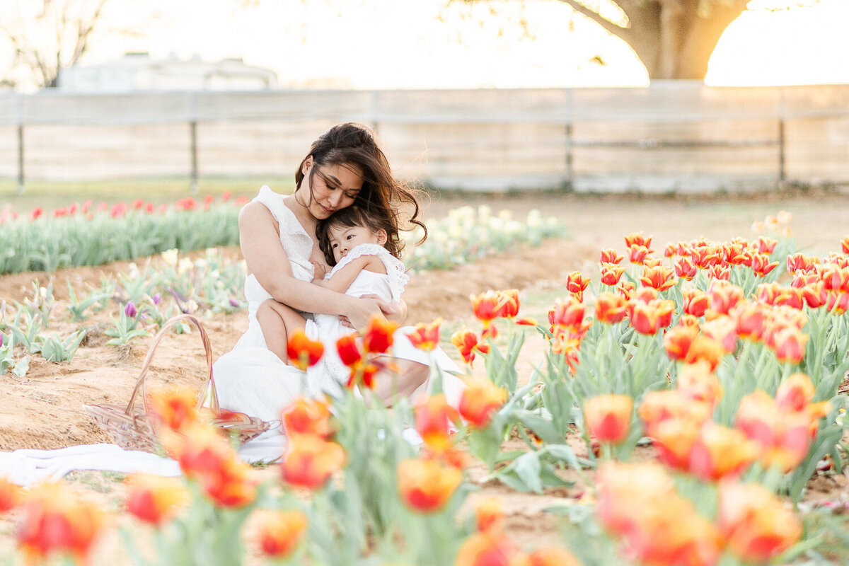 mother holding her child in a field of tulips