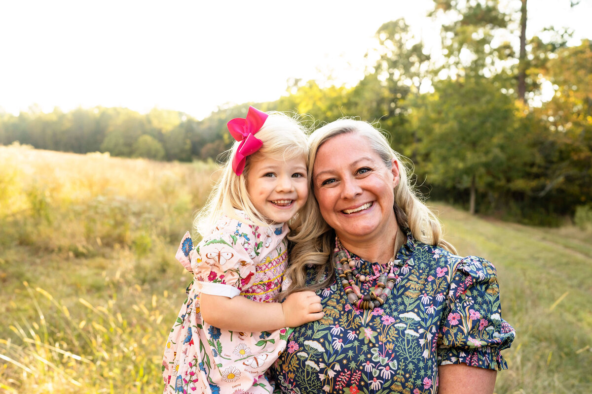 Mother and daughter smiling at the camera with field in the background