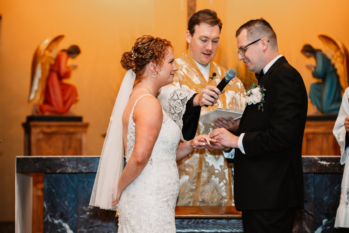 A groom puts on his bride's ring at the altar during vows