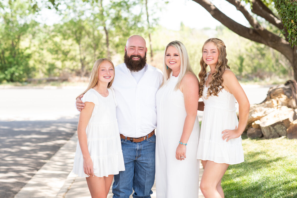 four family members wearing all white pose for their family portrait outside