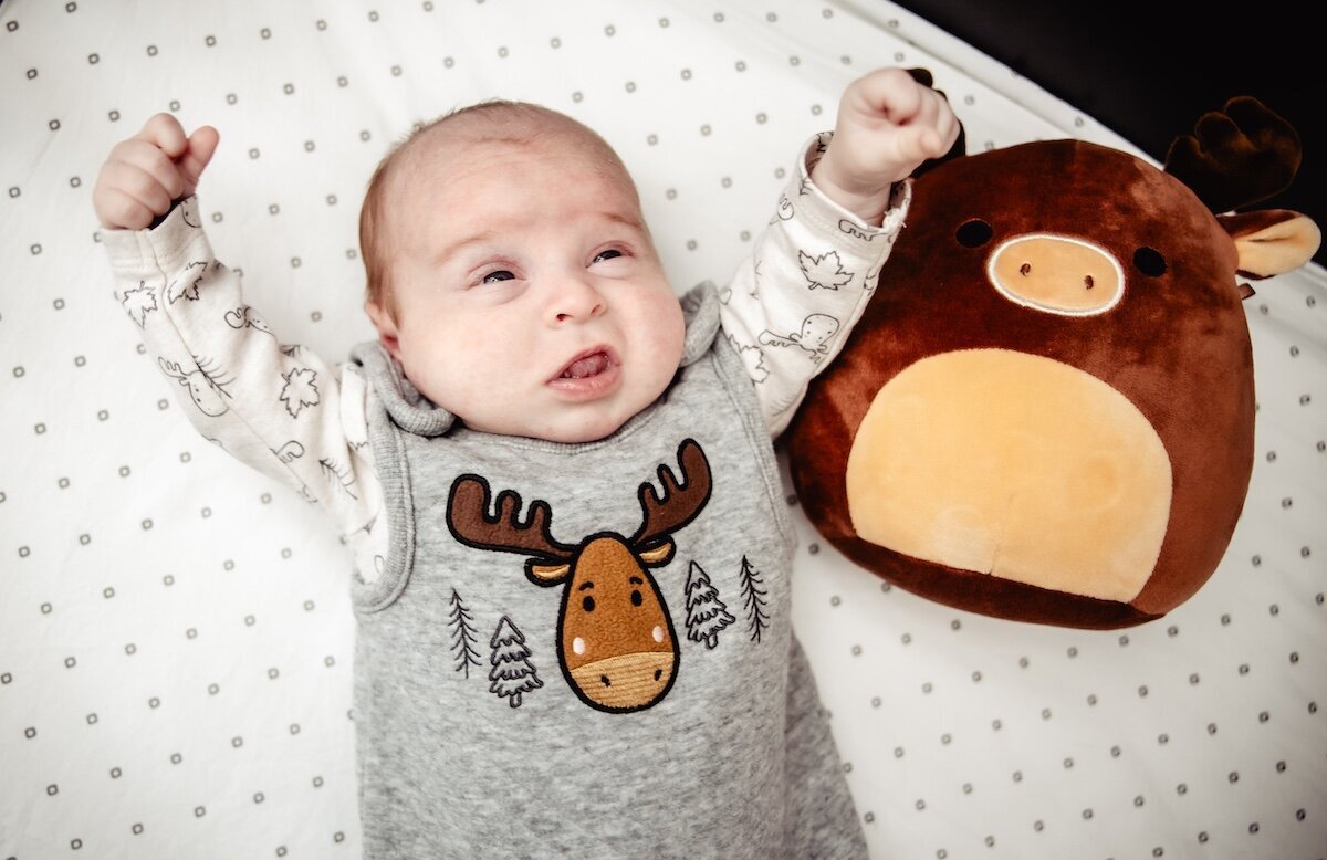 a newborn baby girl stretching in a moose outfit