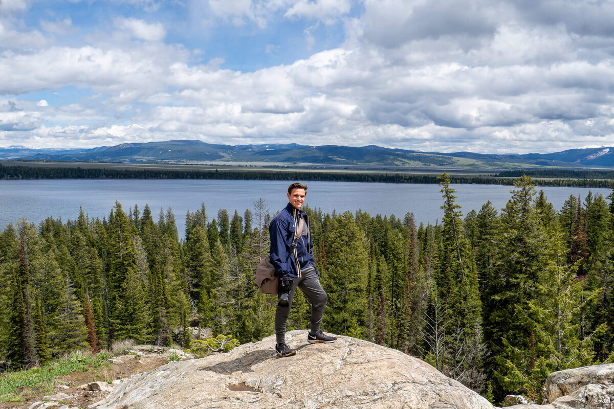 Portrait of Michael Fricke posing with his camera on top of Inspiration Point at Gran Teton national park