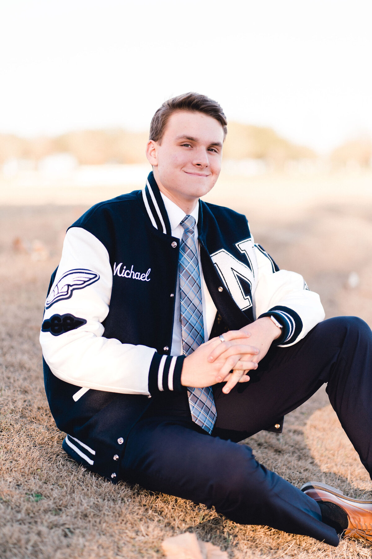 Austin senior boy in letterman jacket. Outside in Austin Texas.