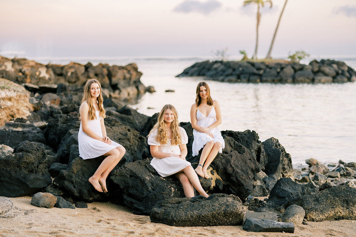 3 girls sitting on lava rocks in Oahu