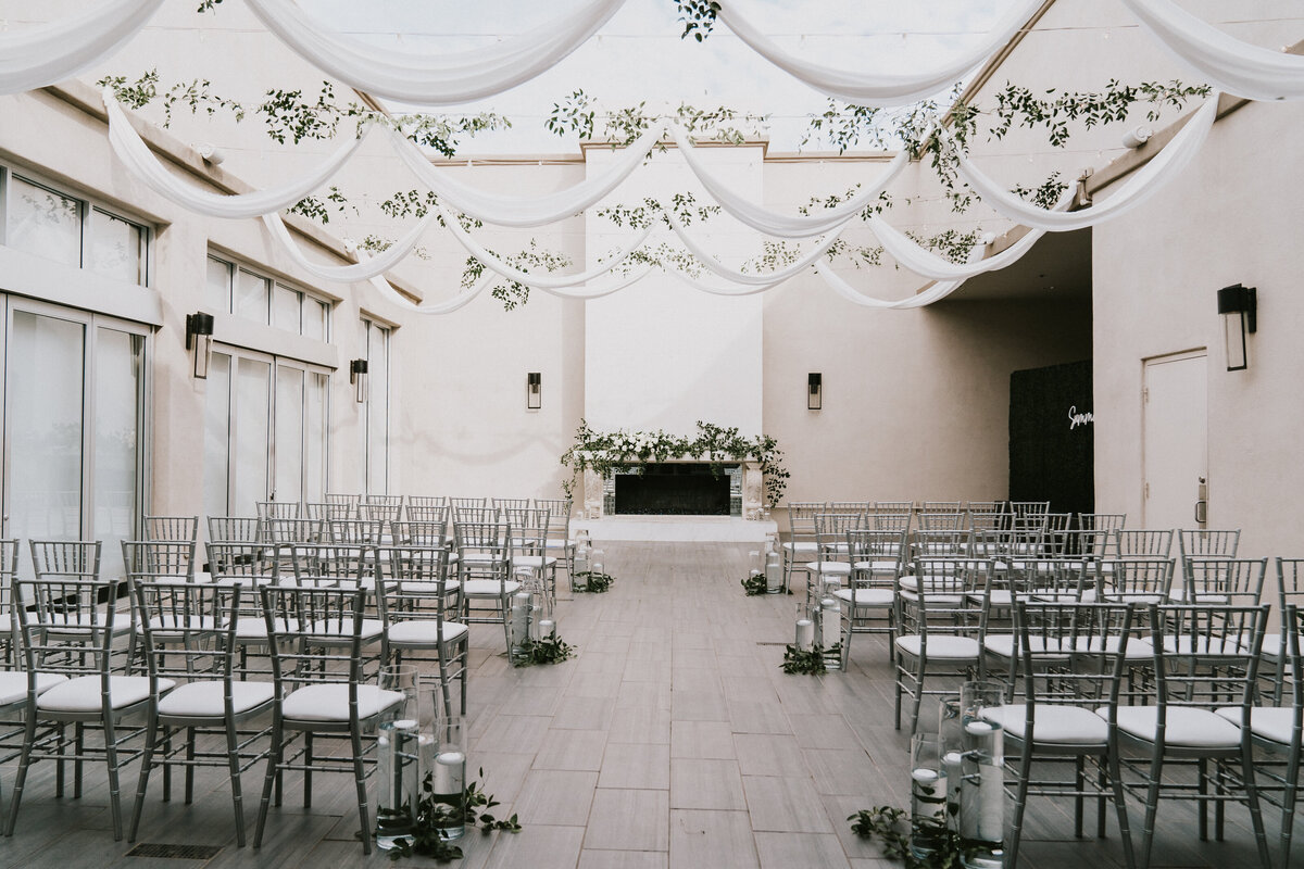 A joyful bride and groom run hand-in-hand through a tunnel of cheering guests outside SoHo63, a popular Chandler wedding and event venue. The black-and-white photo captures the couple smiling as friends and family celebrate around them under a covered outdoor walkway.